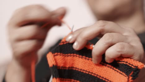 woman's hands doing knit work tie-up hand work with red and black wool