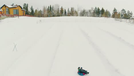 happy tourists wearing warm suit sled down using snow saucer