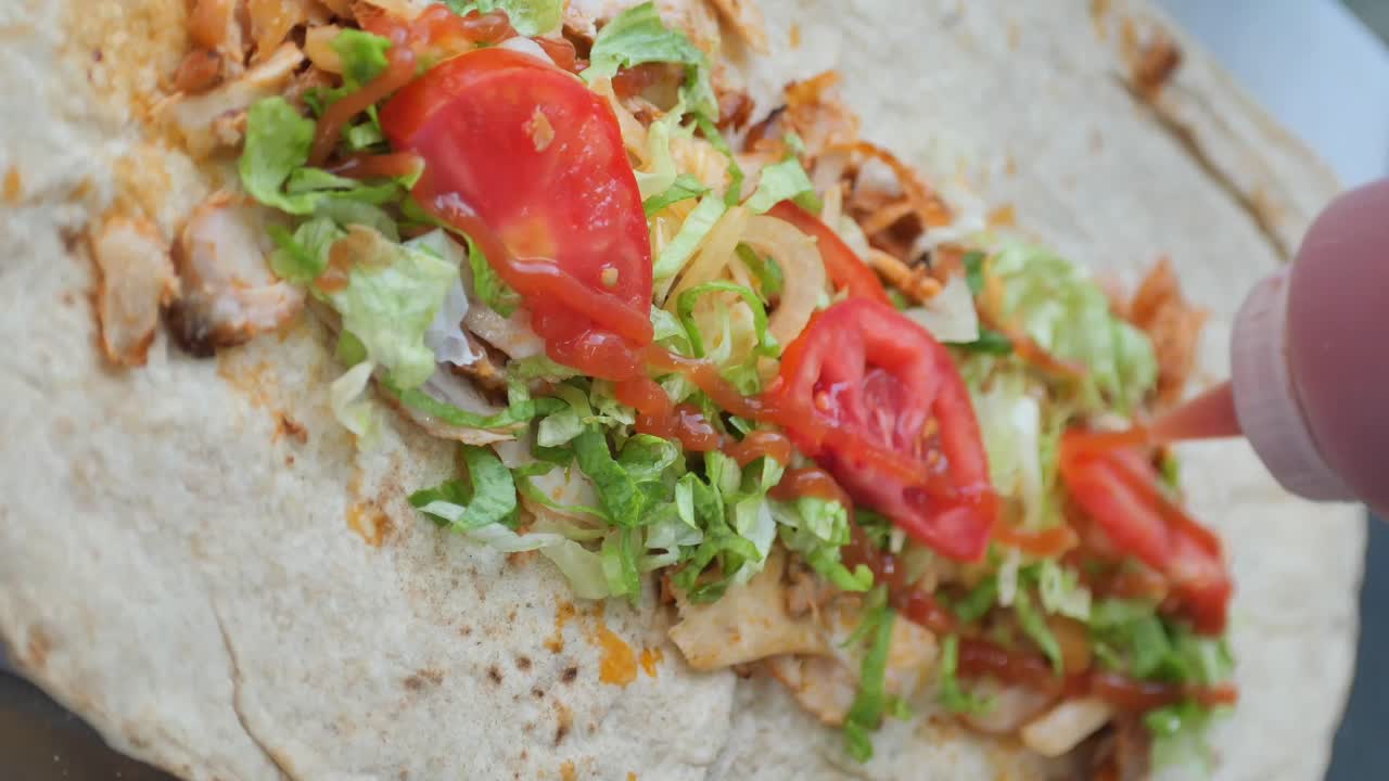 Making a delicious shawarma wrap with fresh ingredients and sauces