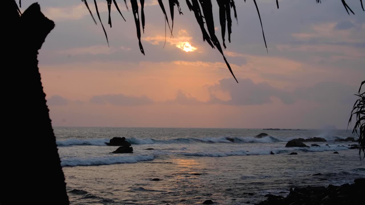 Seduto sotto una palma da cocco a guardare il tramonto con vista sulle onde dell'oceano nel sud dello Sri Lanka