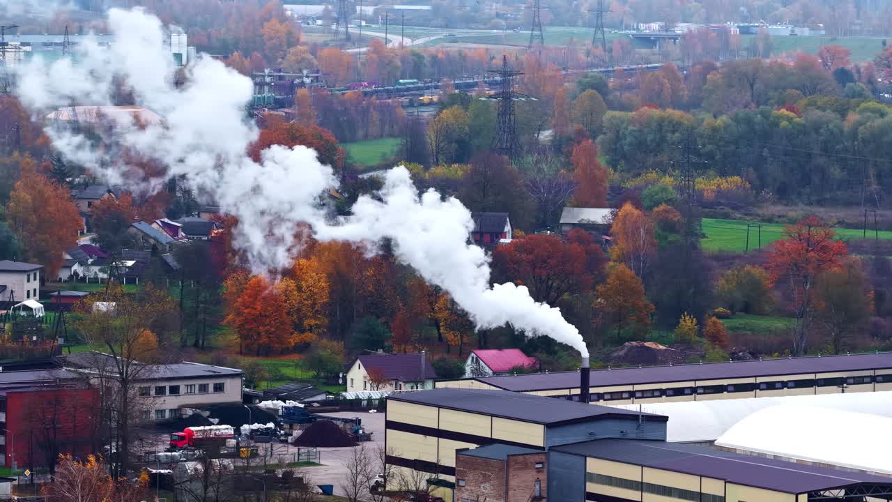 Factory emitting gases in an autumnal forest landscape. Aerial