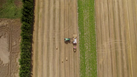 hay bale harvesting season, hard work on field during hot day, aerial top down view