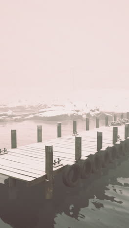 foggy winter morning on a secluded dock with snow covered surroundings