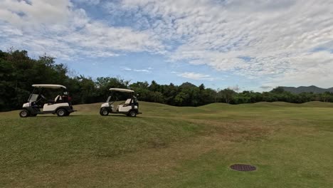 two golf carts moving on a sunny golf course.