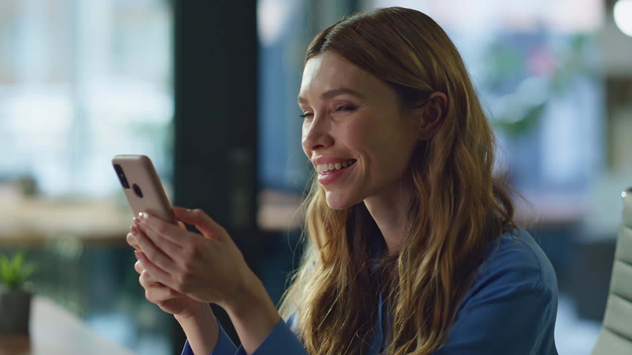 Smiling woman watching social media content on smartphone at office closeup
