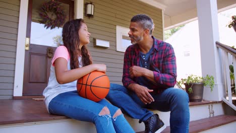 father and daughter discussing basketball on porch of home