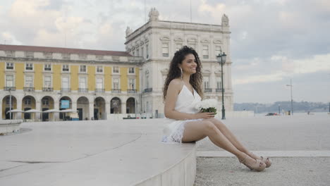 woman in white dress sitting in a european square