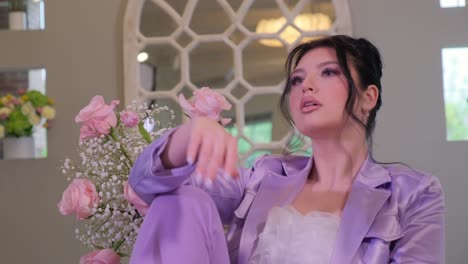 a confident woman in purple holds pink roses exuding elegance a confident woman in a purple suit holds pink roses exuding elegance she then sits in a serene setting reflecting on beauty