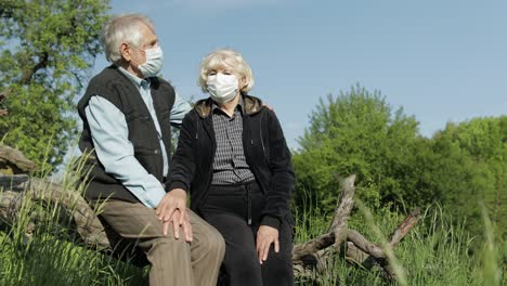 senior couple in medical masks during covid-19 coronavirus quarantine in park