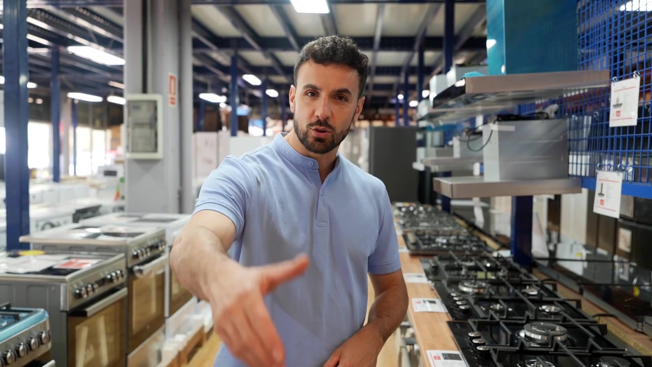 Commesso cordiale che presenta elettrodomestici da cucina in un negozio