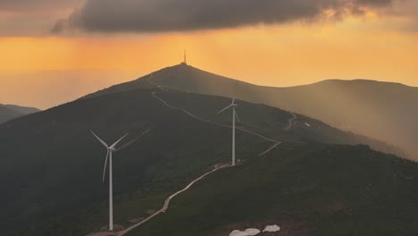 웅장한 풍력 터빈이 있는 극적인 풍경 위에서 놀라운 일몰을 목격하세요.
