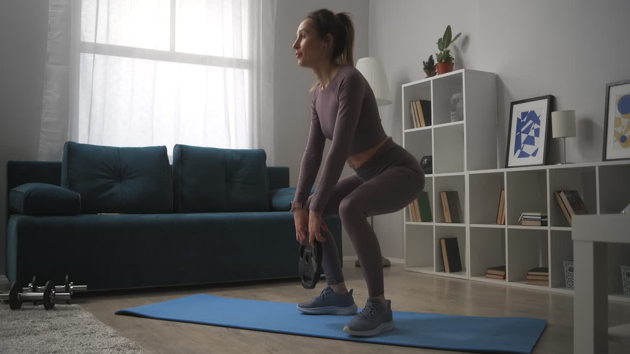 atleta delgada está entrenando culo y piernas agachado con peso en la habitación del apartamento culturismo y ejercicios de fitness en casa estilo de vida saludable