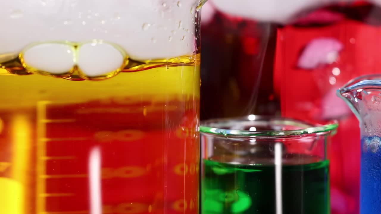 Close-up view of colorful liquids in beakers, showcasing vibrant layers and bubbling reactions.