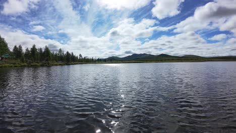 a drone captures breathtaking views of a tranquil lake with mountains and vibrant clouds overhead