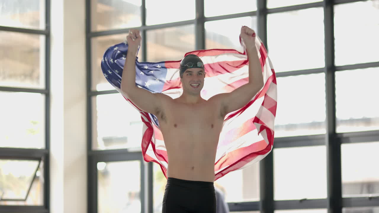 Celebrating victory, Male Swimmer holding American flag with arms raised in triumph