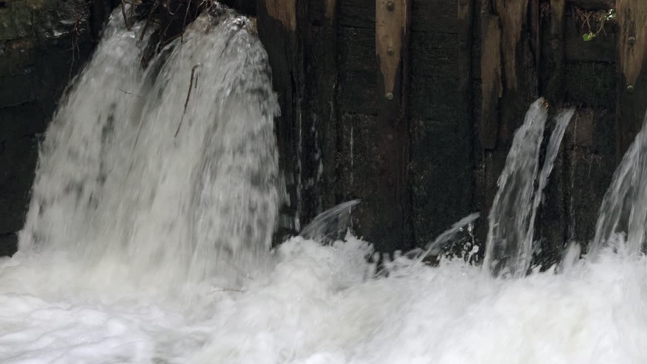 The raging waters of the river Alne in Warwickshire, England as it passes through sluice gates that control the amount of flood water after torrential rainfall