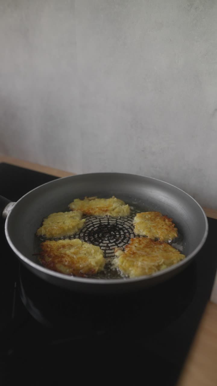 Steger kartoffelpandekager (latkes) på en pande.