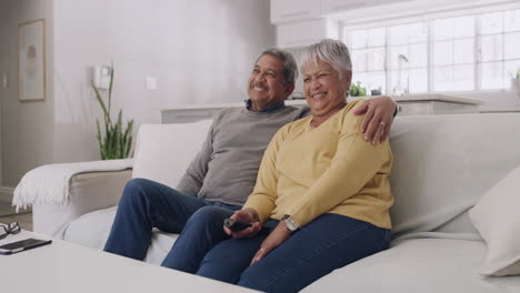 senior couple laughing while watching tv