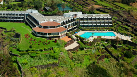 cinematic aerial drone shot of a beautiful resort located on top rocky coastline in sao miguel island, azores - portugal