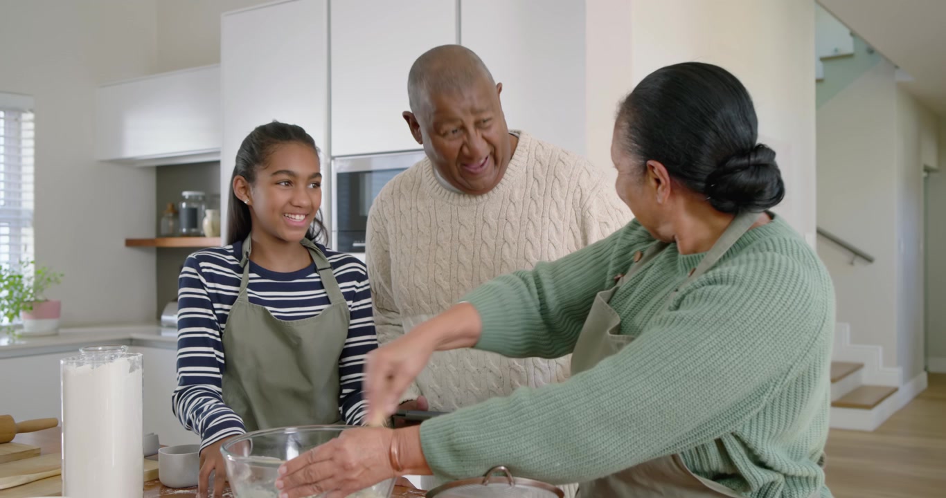 African American family preparing batter in bowl at kitchen island senior whisking, man urging girl