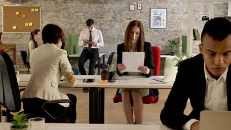 business people of mixed ethnicity working in office, asian woman giving to caucasian woman documents, woman looking at papers