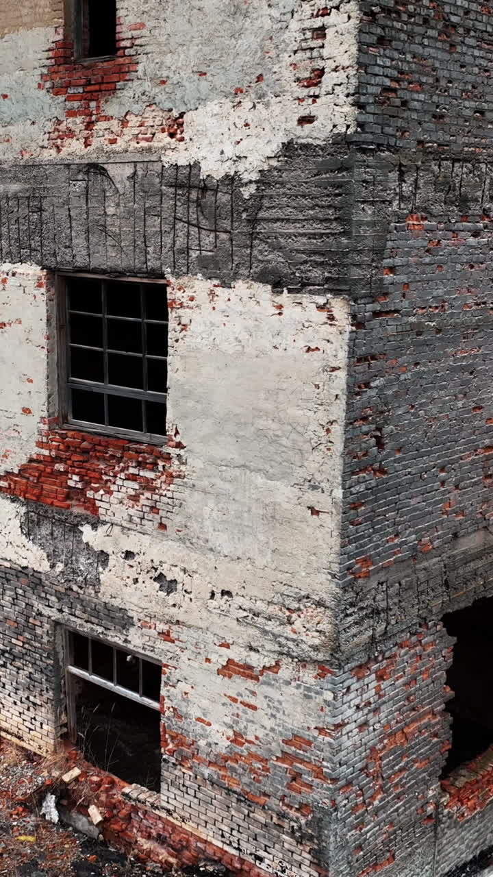 Bare brick walls and window holes in the bombed buildings. Ruined architecture resulting from air strike. Drone shot. Vertical video