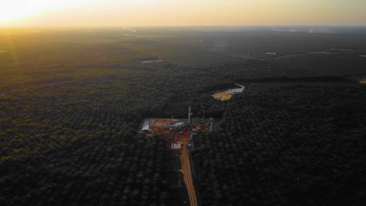 imágenes cinematográficas de drones de 4k de la estructura del equipo de la plataforma de perforación en tierra para la exploración y explotación de petróleo en medio de la jungla rodeada de palmeras durante la puesta de sol y el alto precio del petróleo
