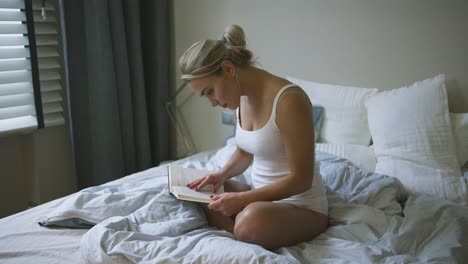 woman in underwear reading on bed