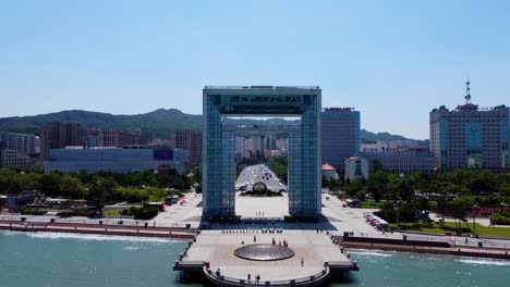 Cinematic-aerial-pullback-reveals-Xingfu-park-arch-and-mini-dome-artwork,-Asian-city-skyline