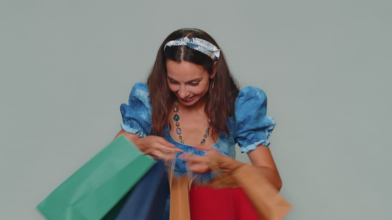 행복한 미소 짓는 젊은 여성은 쇼핑 가방을 보여주고, 광고 할인, 낮은 가격에 놀랐습니다