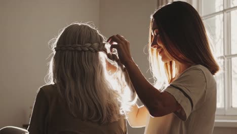 woman braiding hair of elderly woman