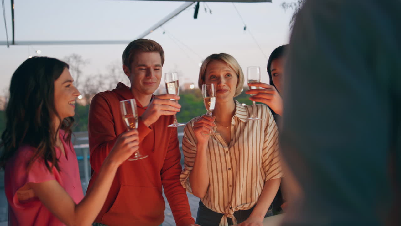 amigos multirraciales brindando champán en la terraza del bar al atardecer. grupo celebrando