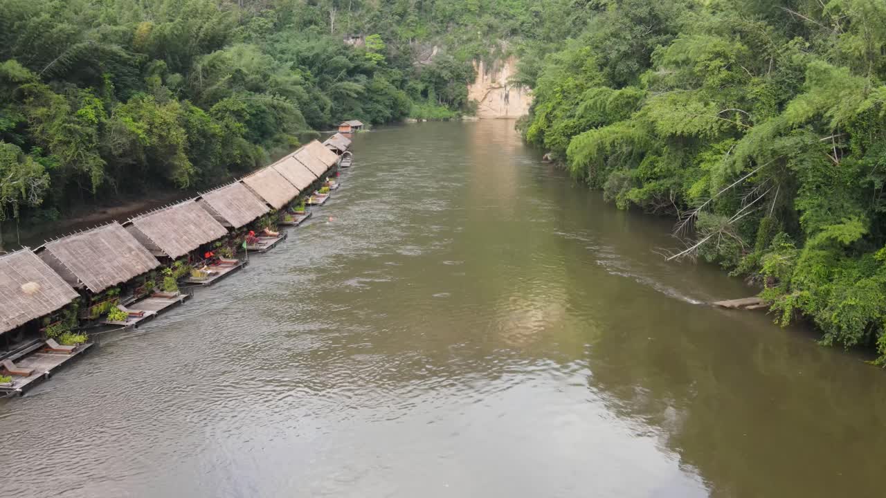 vista aérea de drones que viajan por el río kwai, con hoteles flotantes rodeados de una atmósfera parecida a la jungla en kanchanaburi, tailandia