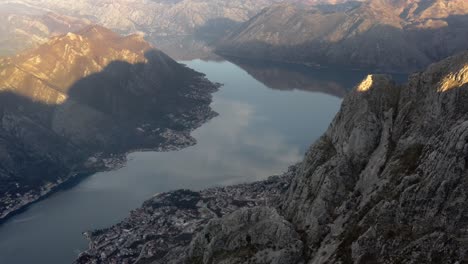 Aerial-view-of-calm-water-of-winding-bay-interrupted-by-huge-cliffs-and-mountains-during-sunrise