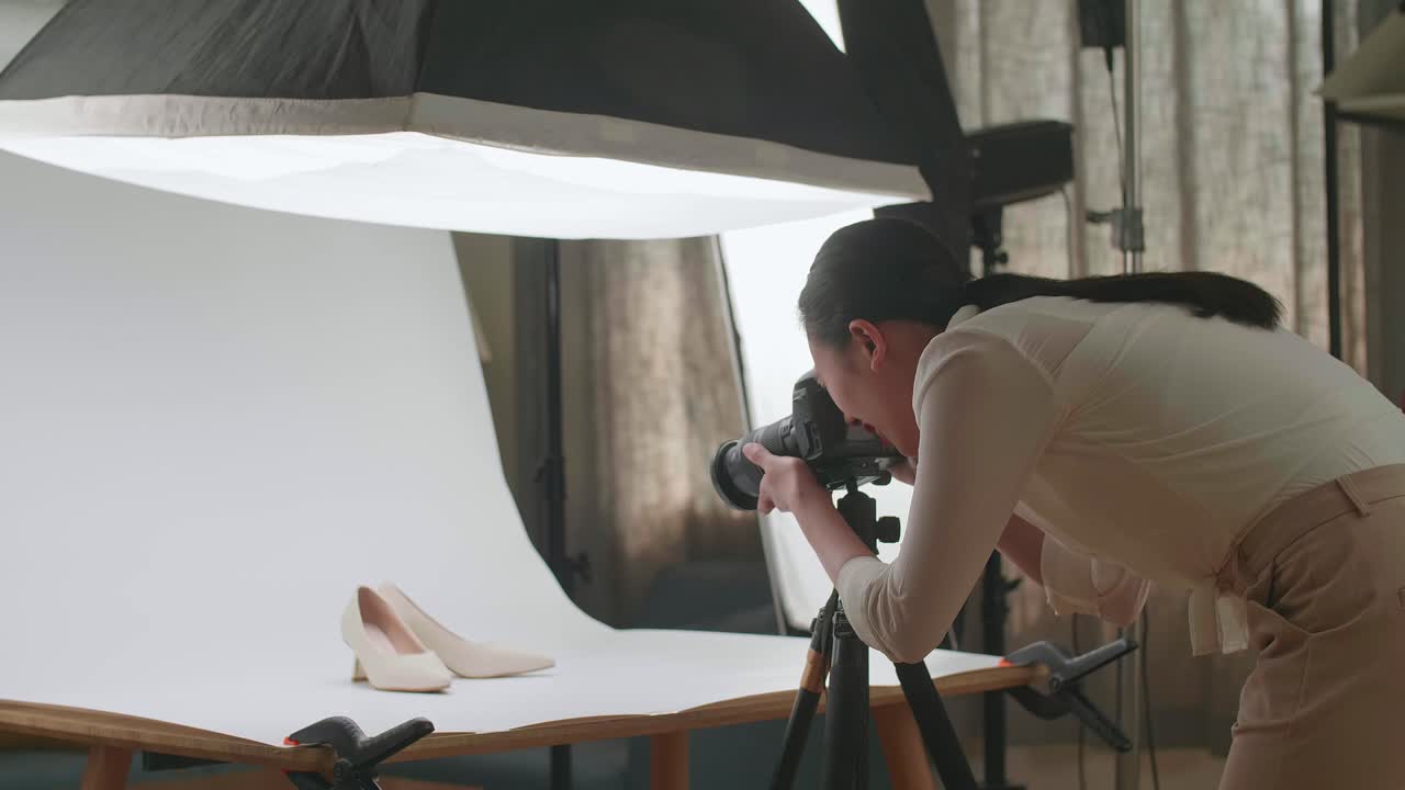 fotógrafa asiática tomando fotos de zapatos femeninos en su estudio casero