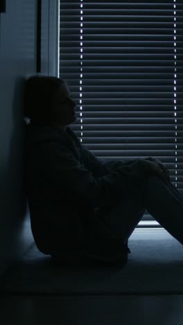 silhouette of a woman sitting alone in a dark room