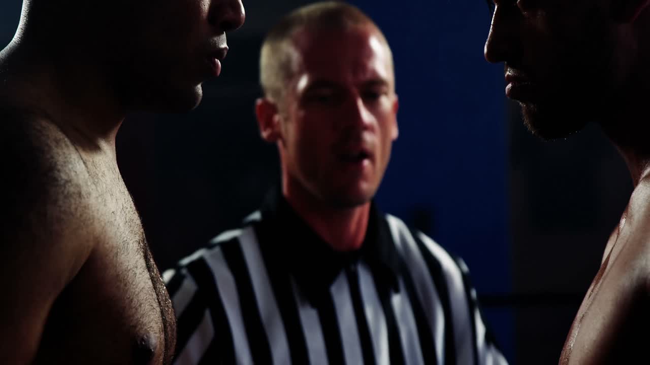 Referee interacting with boxers before starting match