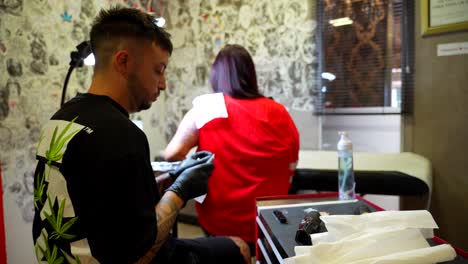 tattoo artist starting to draw a tattoo on the arm of a female customer