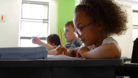 Side-view-of-African-american-schoolgirl-studying-at-desk-in-classroom-at-school-4k