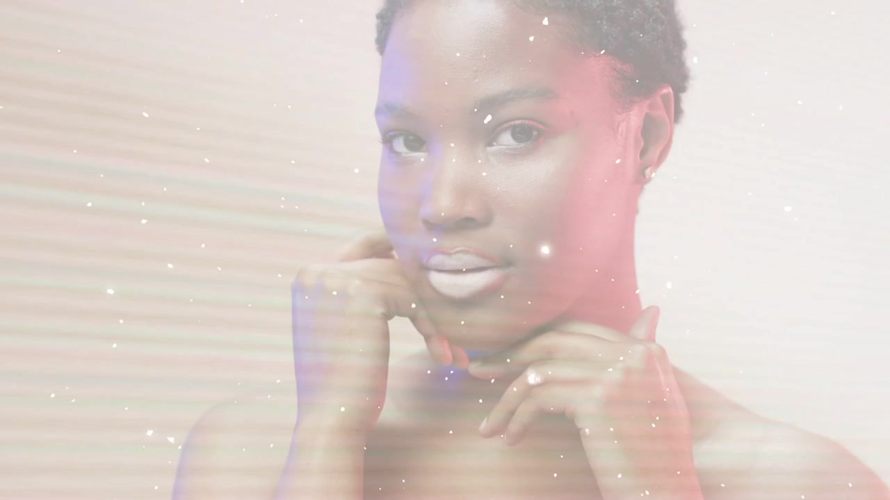 Beauty model opening eyes, framing chin as haze and sparks intensifying across studio showing lips