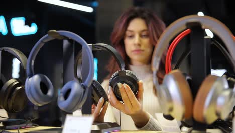 woman with curly hair choosing headphones in speaker system store. . high quality 4k footage