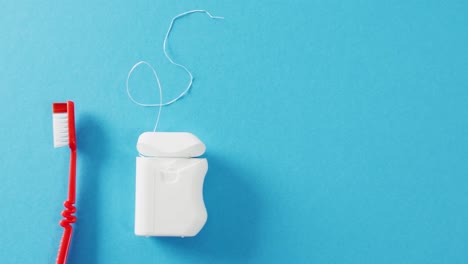 video of close up of toothbrush and floss on blue background