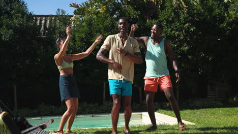 diverse friends laughing and dancing by pool, enjoying sunny day outdoors together