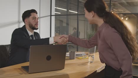 female candidate and male interviewer shaking hands in office before job interview