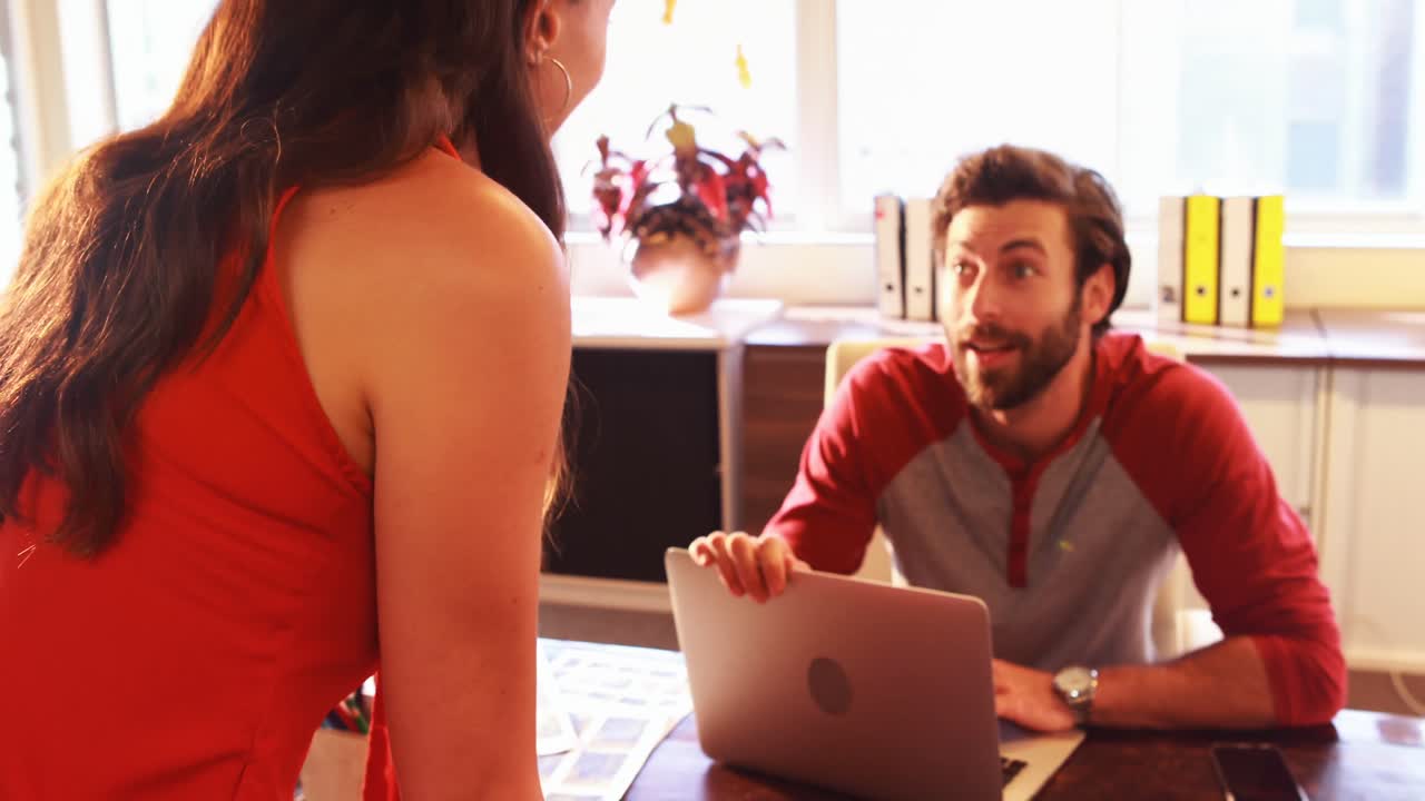 diseñadores gráficos masculinos y femeninos interactuando mientras trabajan