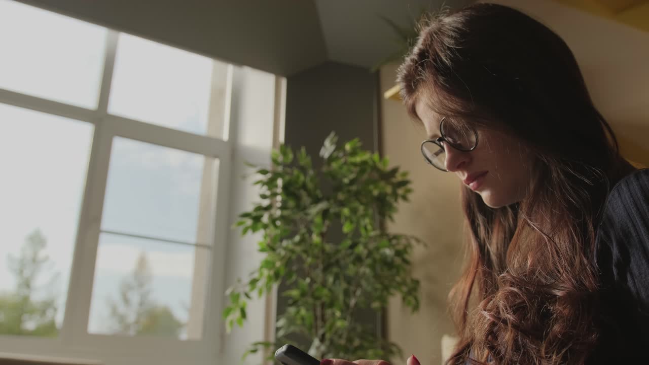 Woman using smartphone in a home interior.