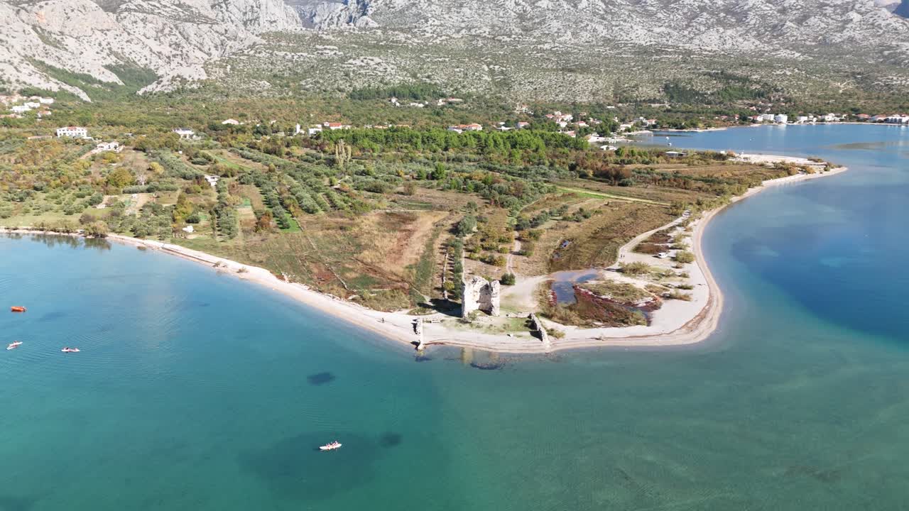 Hırvatistan, Starigrad-Paklenica'da Adriyatik Denizi kıyısındaki tarihi Večka Kula Kulesi'nin geniş hava drone panoraması. Uzun sahil şeridi ve görkemli Velebit dağları çarpıcı bir doğal manzara yaratıyor