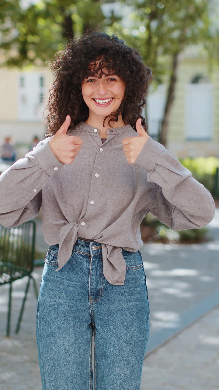 Happy young woman girl showing thumbs up like sign something good positive feedback on city street