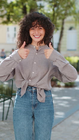 happy young woman girl showing thumbs up like sign something good positive feedback on city street