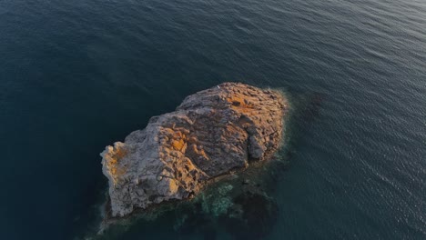 Eine-Kreisförmige-Aufnahme-Einer-Felsigen-Insel-Während-Des-Sonnenuntergangs,-Aufgenommen-Mit-Einer-Drohne